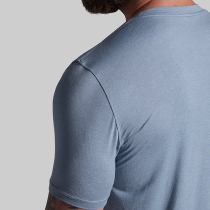 Person wearing a light blue t-shirt on a gray background