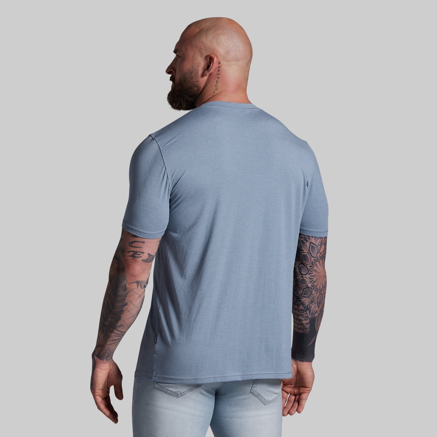 Man wearing a light blue t-shirt and pants on a gray background
