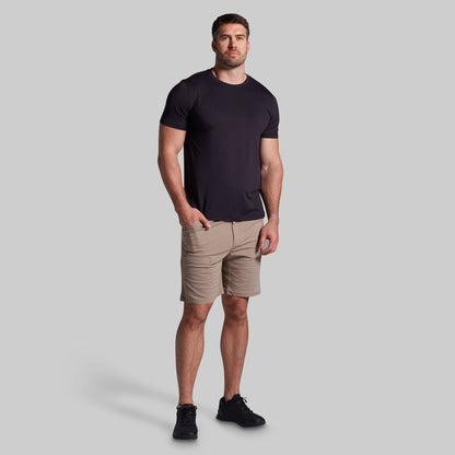 Man wearing a black t-shirt and beige shorts on a gray background