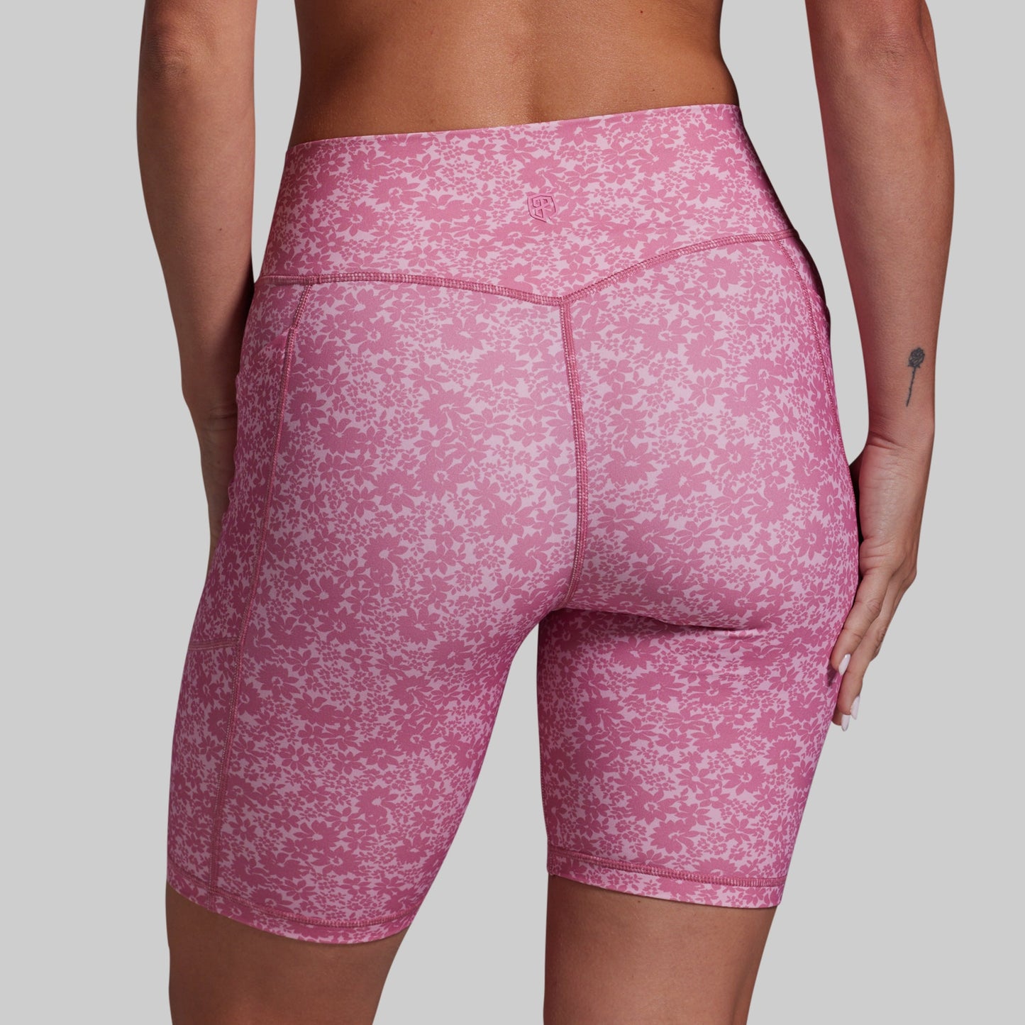 Pink patterned shorts worn by a person on a gray background