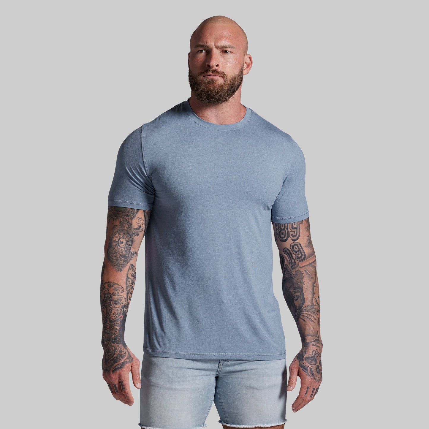 Man wearing a light blue t-shirt and shorts against a gray background