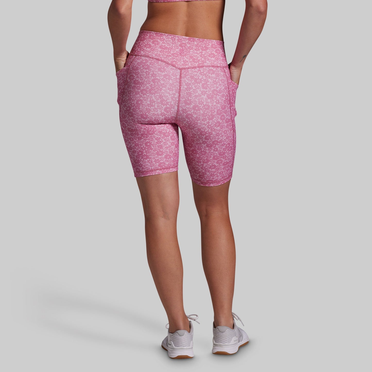 Person wearing pink athletic shorts on a gray background
