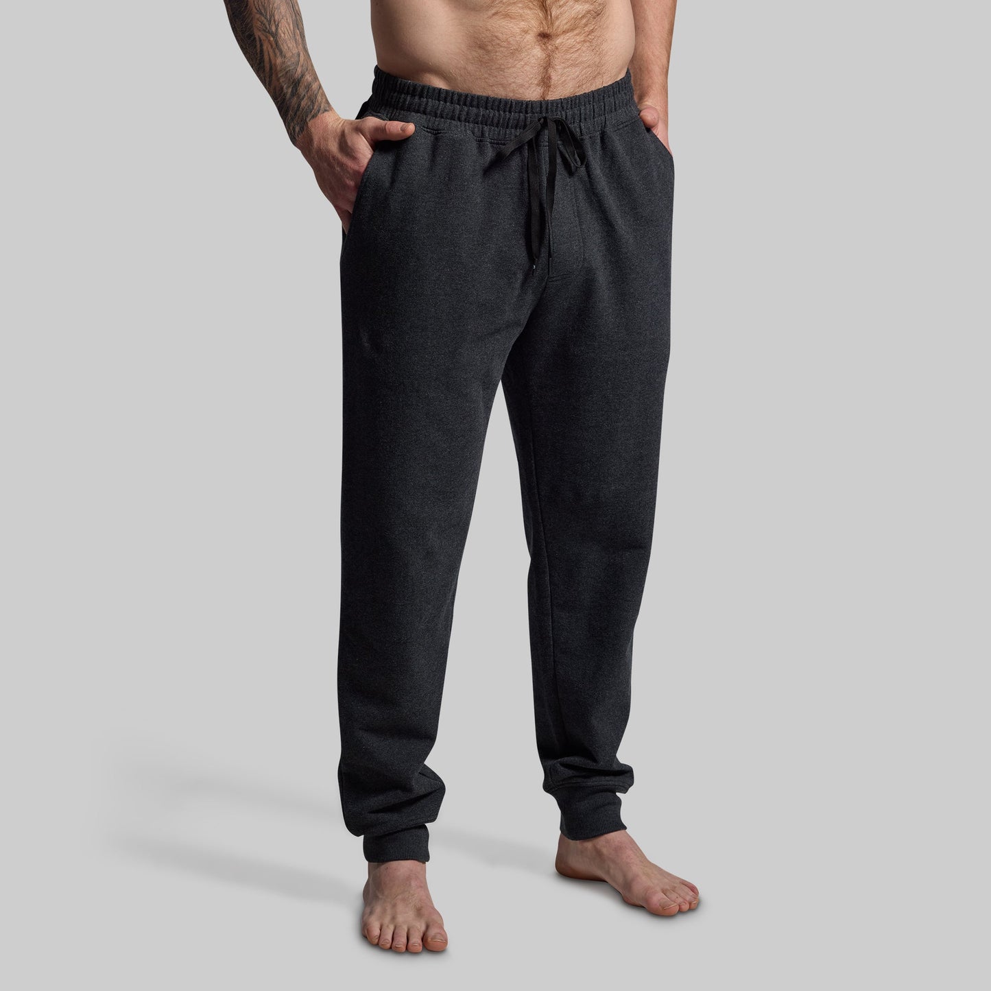 Person wearing dark gray jogger pants on a light gray background