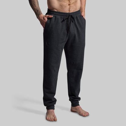 Person wearing dark gray jogger pants on a light gray background
