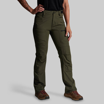 A model wearing olive green technical cargo pants with brown hiking boots, shown from the waist down against a solid gray background.