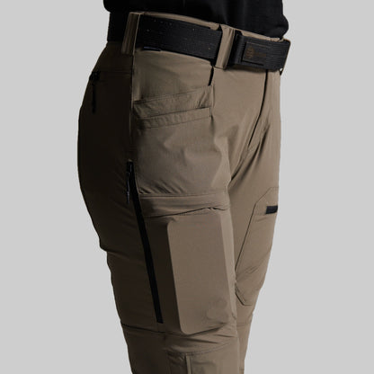 Close-up side view of storm grey cargo pants worn with a black belt, showing side pockets, zippered cargo pockets, and a black waistband on a light gray background.