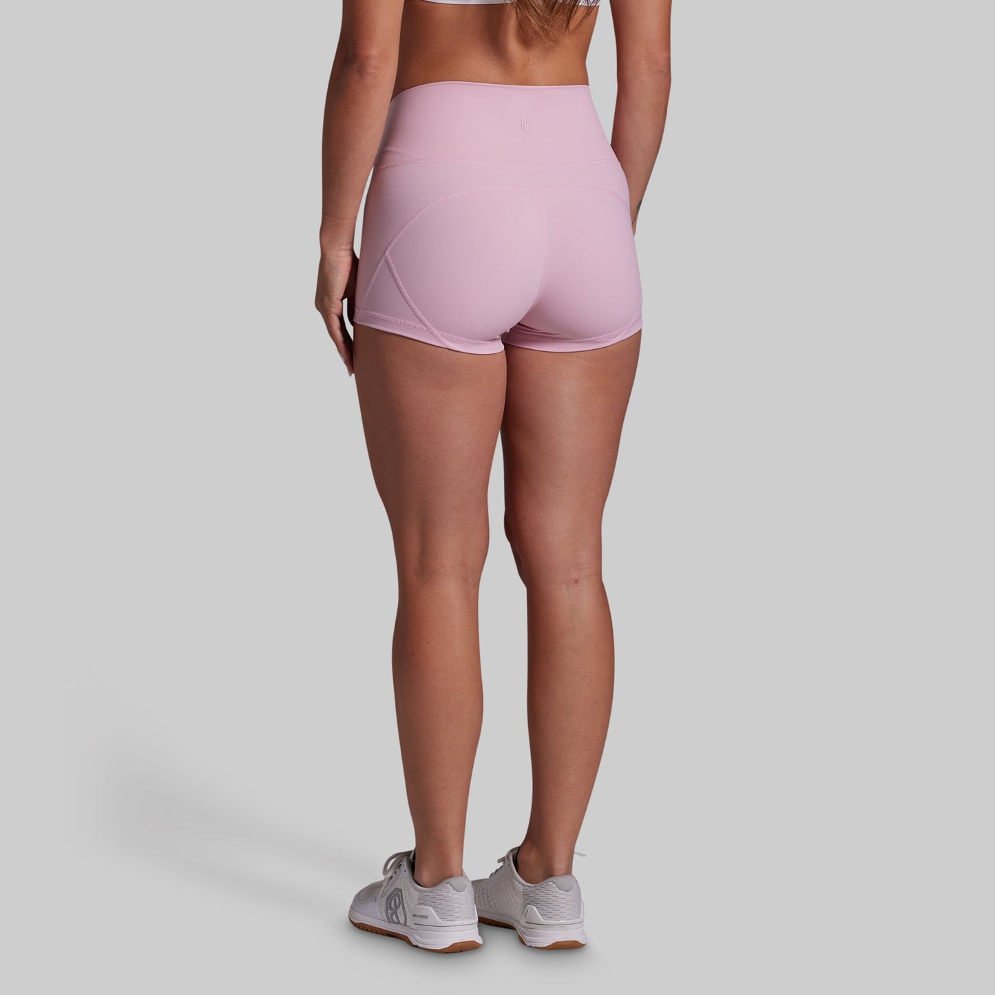 Person wearing pink athletic shorts on a plain background