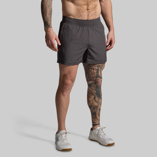 Man wearing gray shorts on a plain background