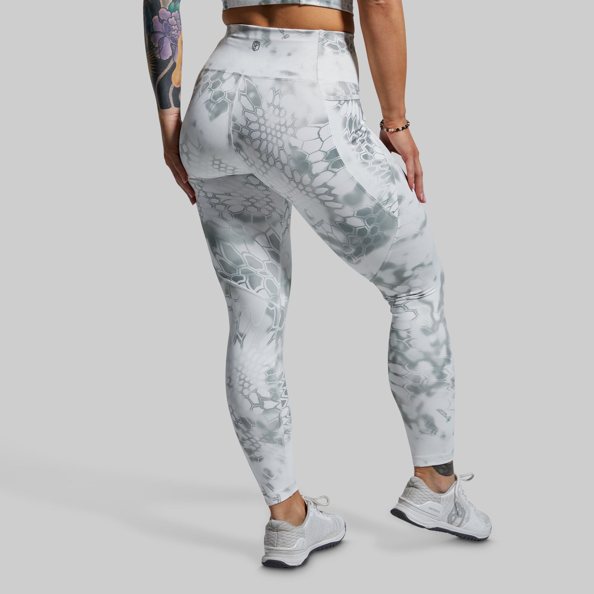 Person wearing gray and white patterned leggings on a plain background