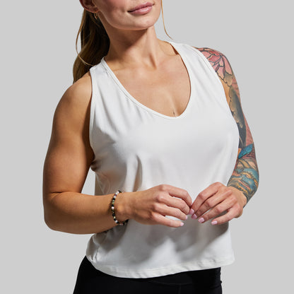 Woman wearing a white tank top with a neutral background