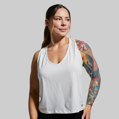 Woman wearing a white tank top against a plain background