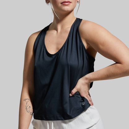 Person wearing a black sleeveless top with a plain background