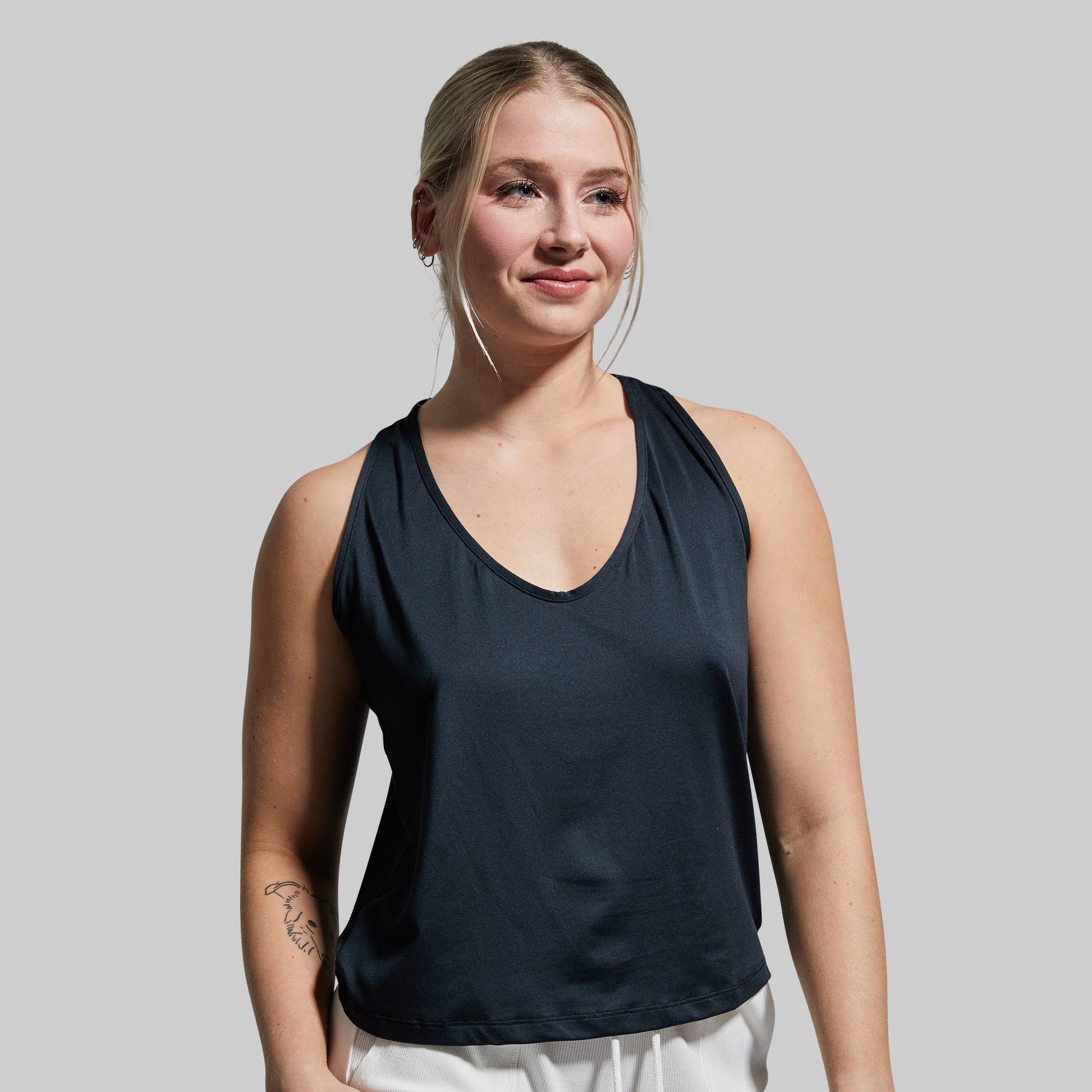 Woman wearing a black sleeveless top against a plain background