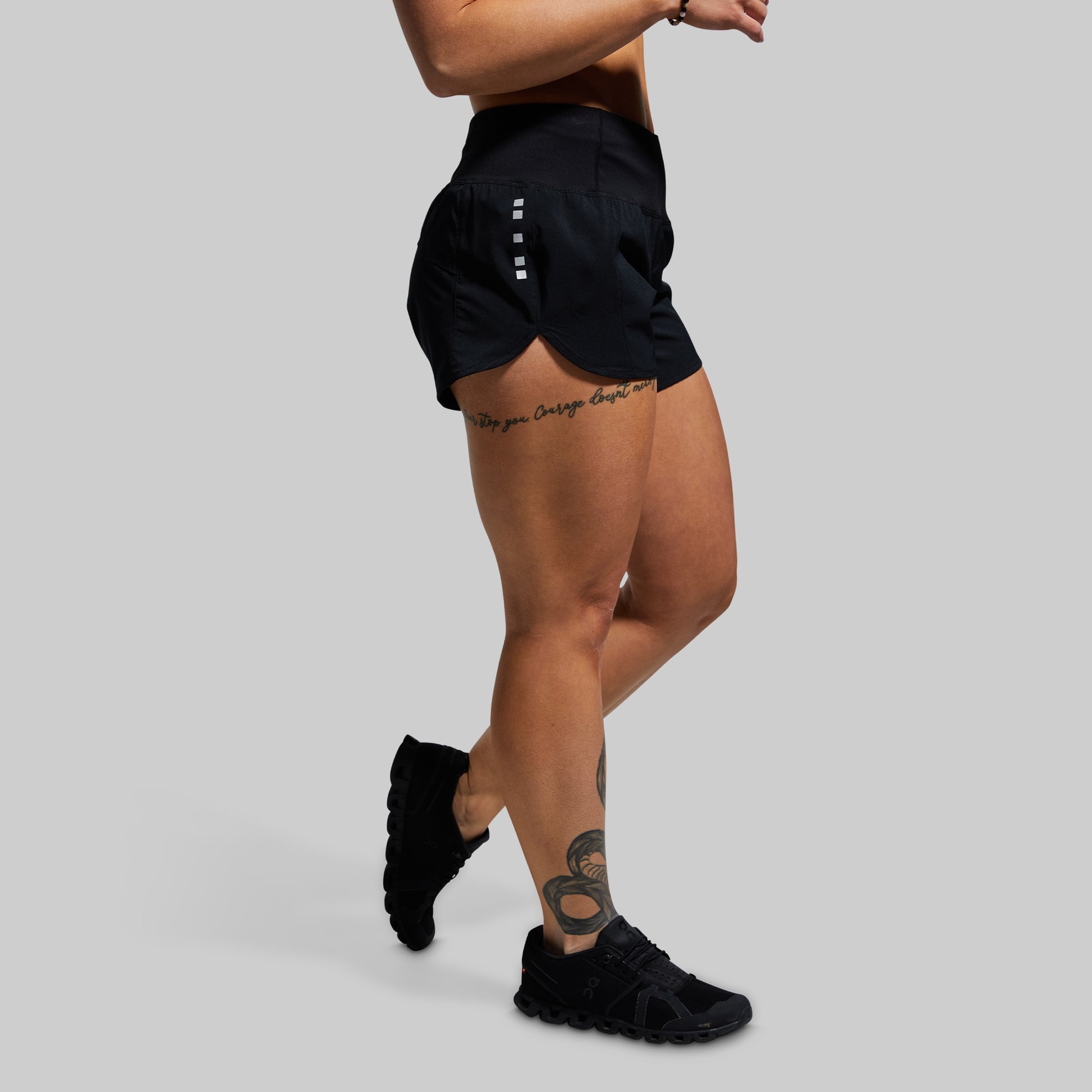 Person wearing black athletic shorts and shoes on a gray background