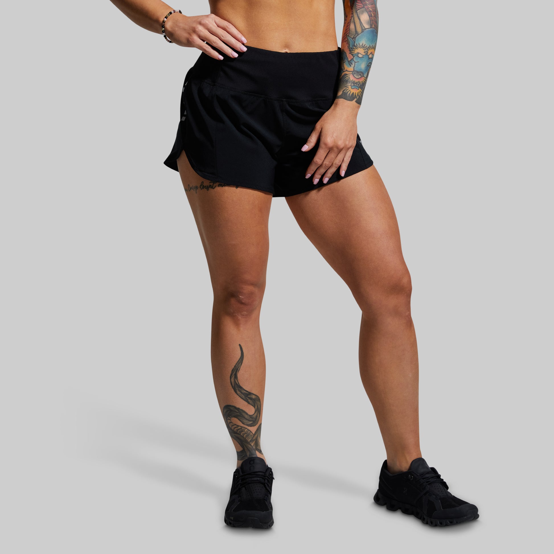 Person wearing black athletic shorts and black sneakers on a gray background