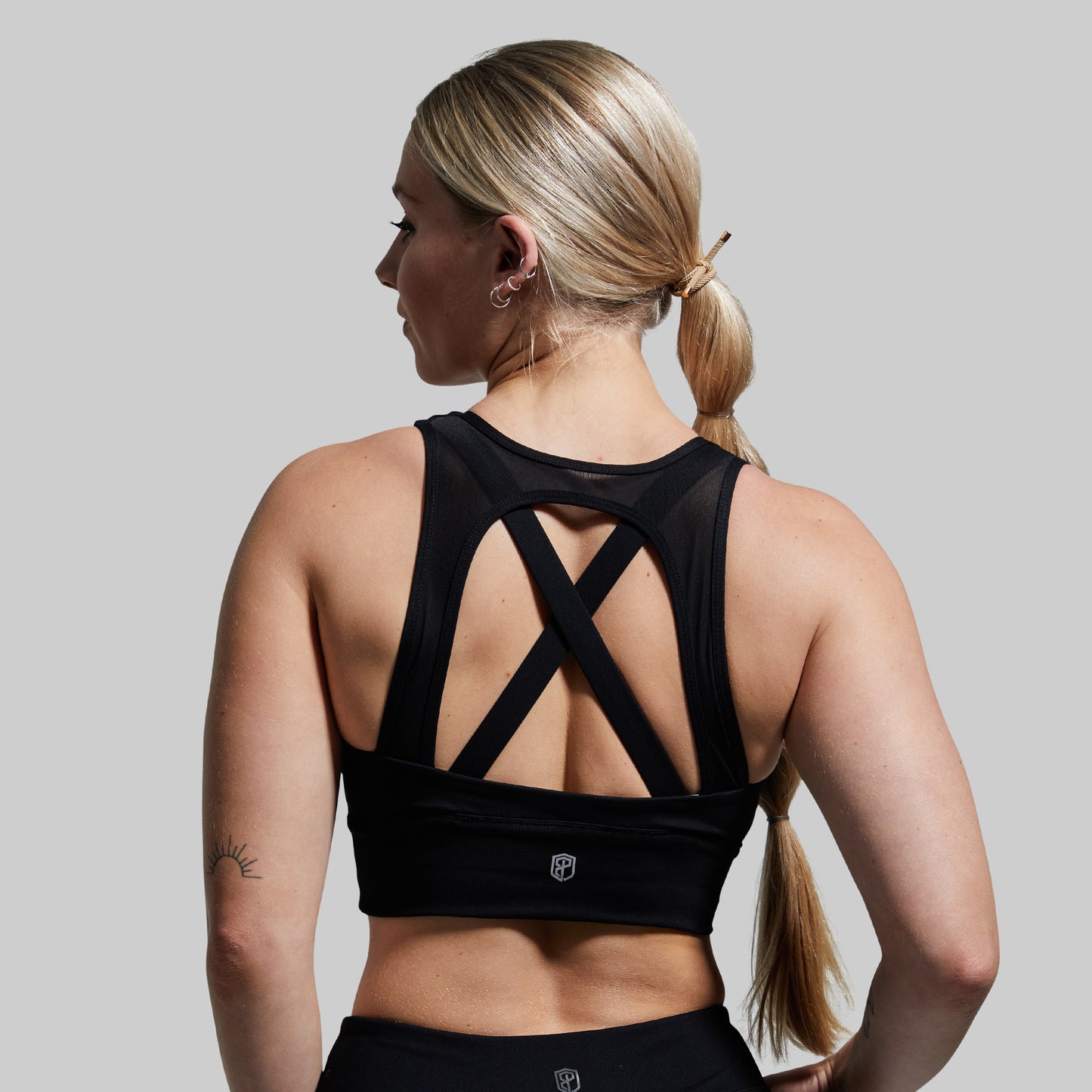 Woman wearing a black sports bra with a gray background