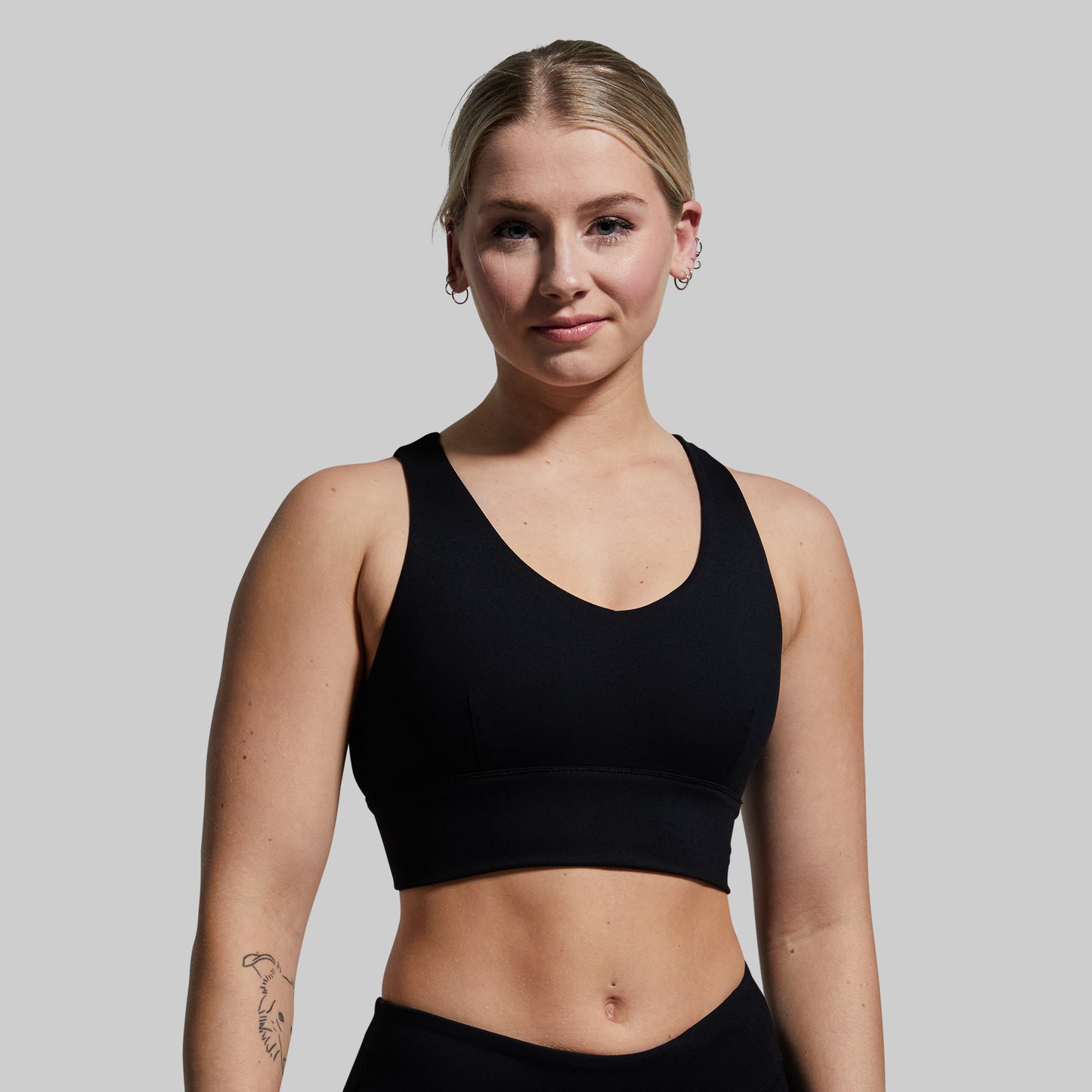 Woman wearing a black sports bra against a plain background