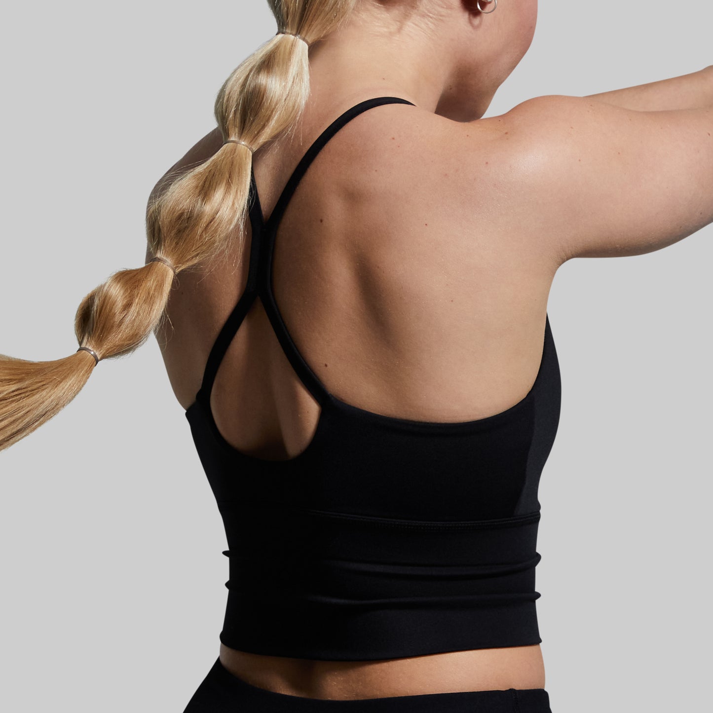 Person wearing a black sports bra with a neutral background