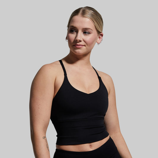 Woman wearing a black sports bra against a plain background