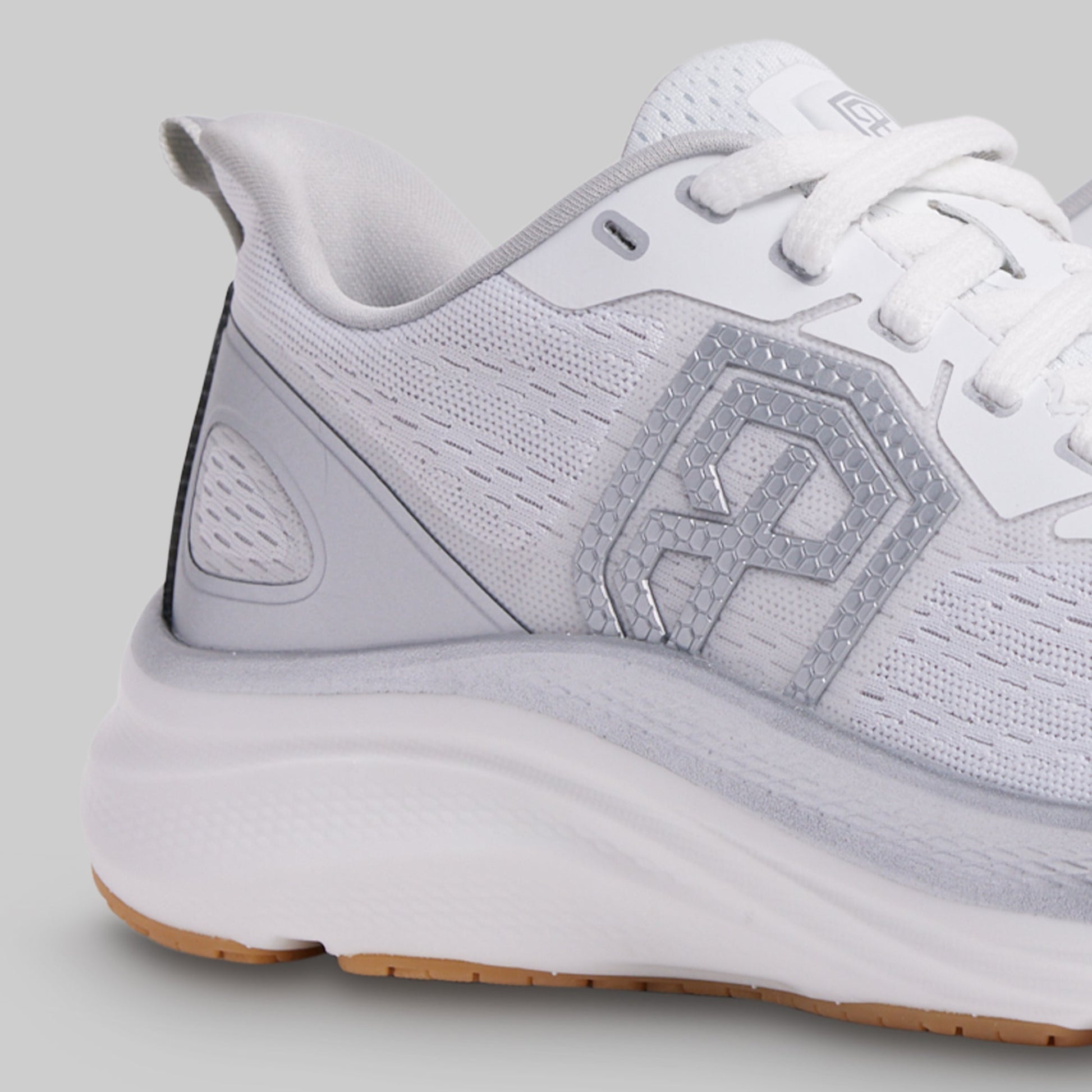 White athletic shoe with a brand logo on a gray background