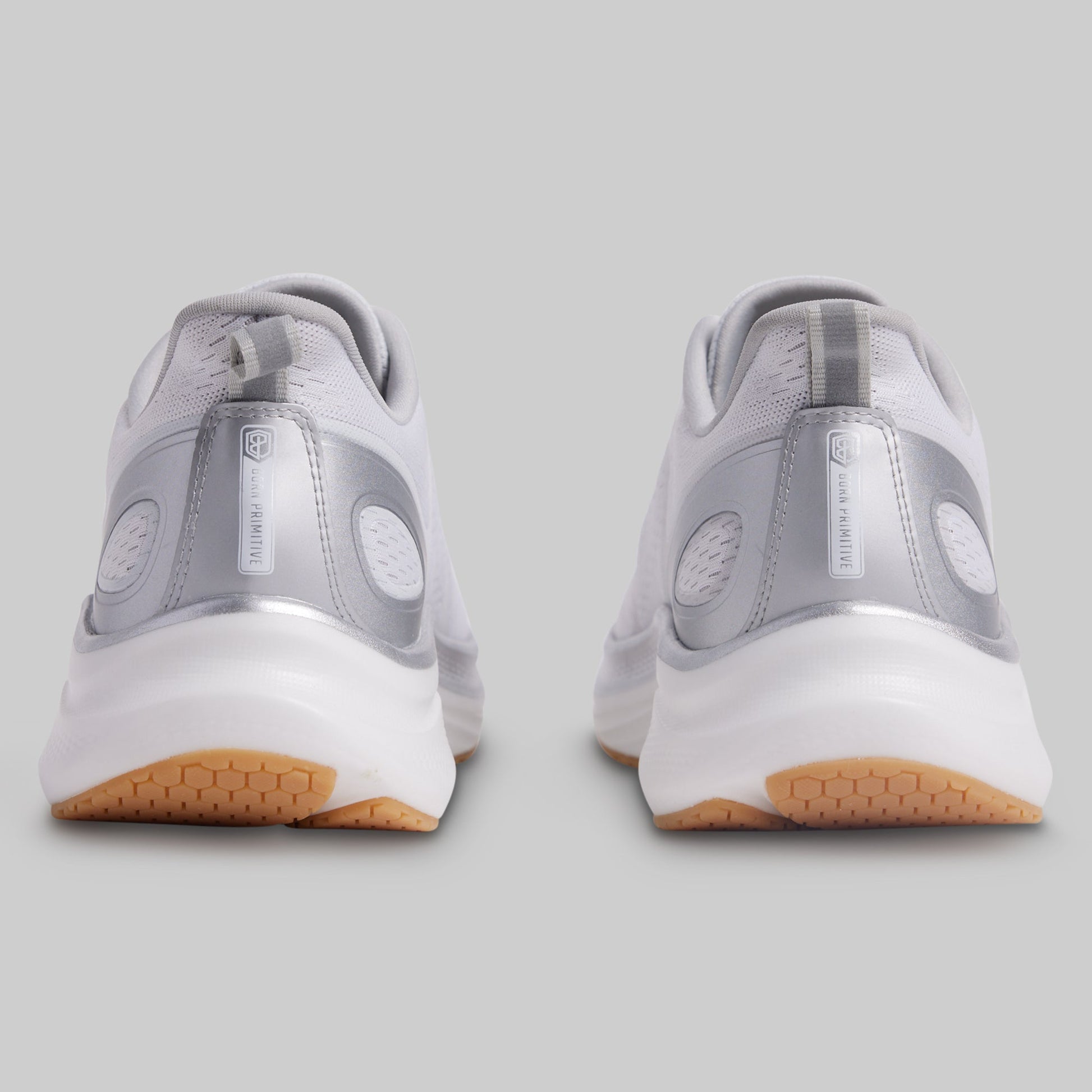 Gray athletic shoes with white soles and brown soles on a gray background