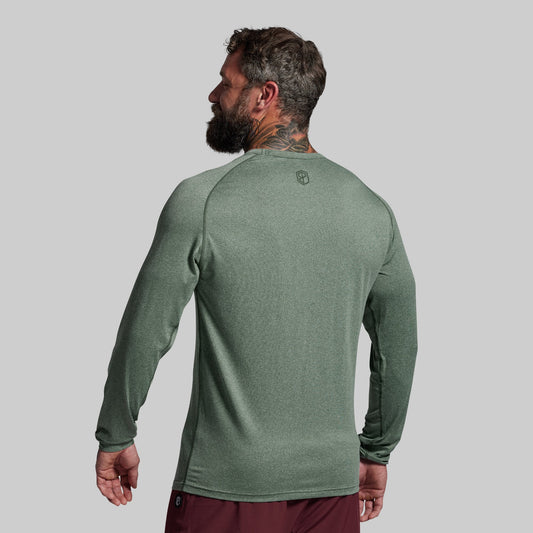 Man wearing a green long-sleeve shirt on a gray background
