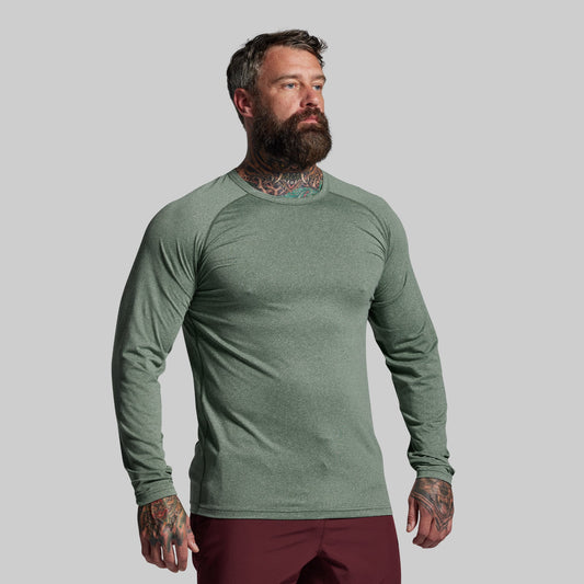Man wearing a green long-sleeve shirt against a gray background