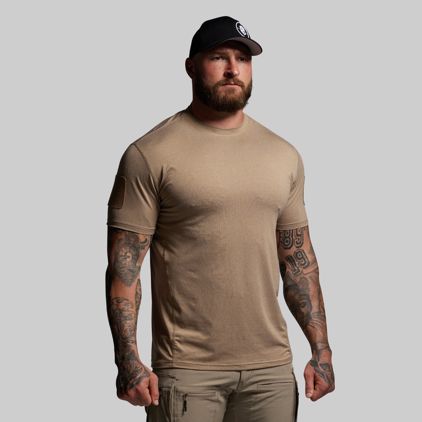 Man wearing a brown t-shirt and cap on a gray background