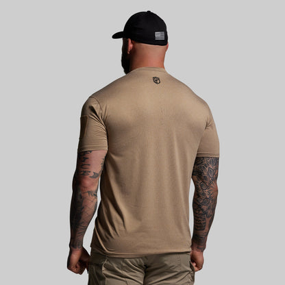 Man wearing a beige t-shirt and cap with a logo on a gray background