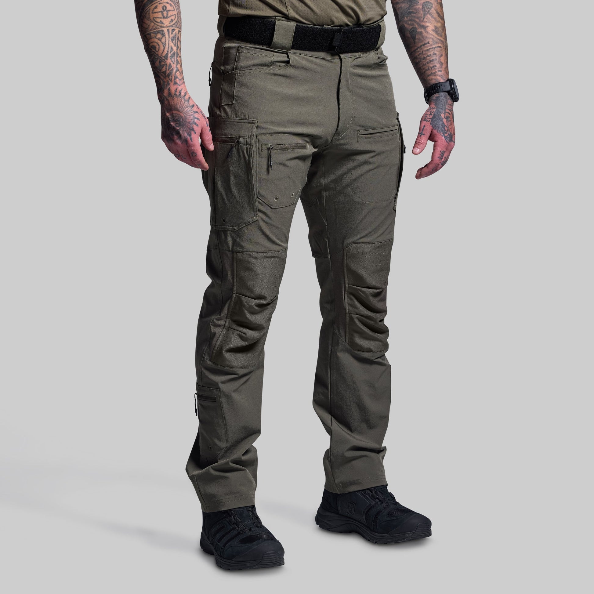 Person wearing green tactical pants on a gray background