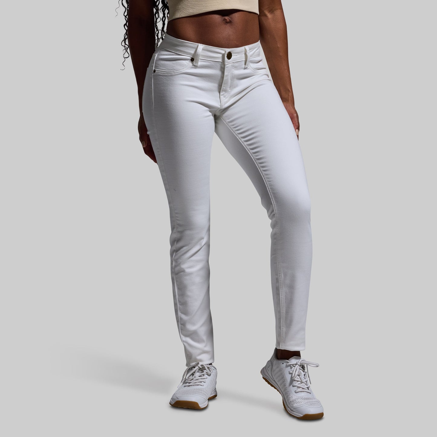 Person wearing white jeans on a plain background