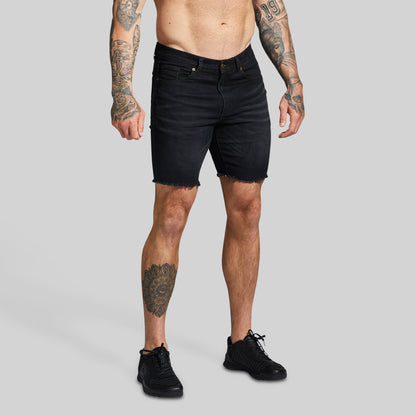 Person wearing black jean shorts on a gray background