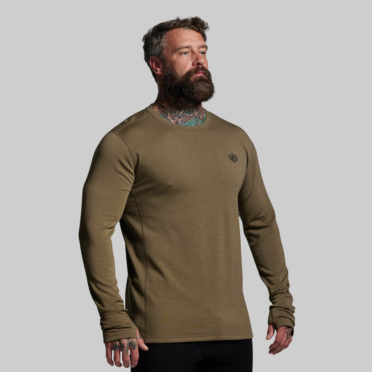 Man wearing a green long-sleeve shirt against a gray background