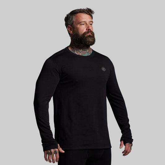 Man wearing a black long-sleeve shirt with a small logo on a gray background