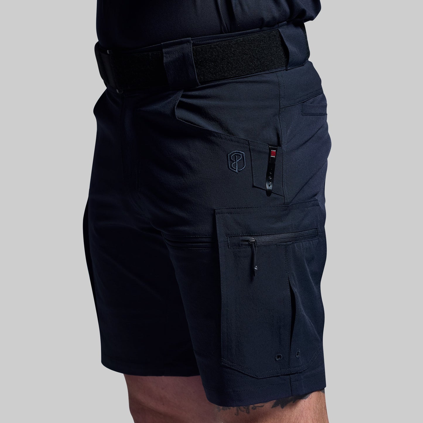 Blue tactical shorts with multiple pockets on a gray background