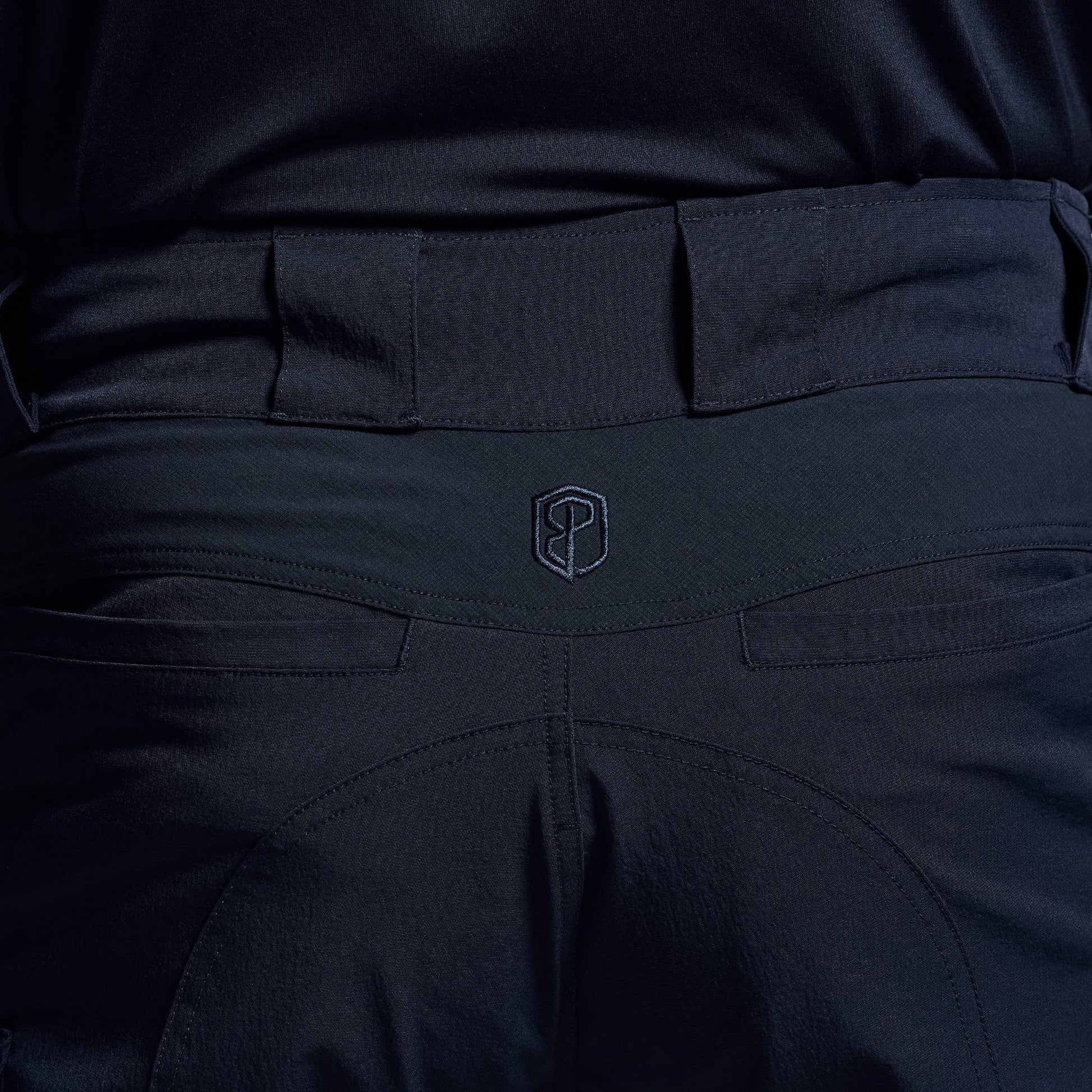 Close-up of dark blue tactical shorts with a visible brand logo on the waistband.