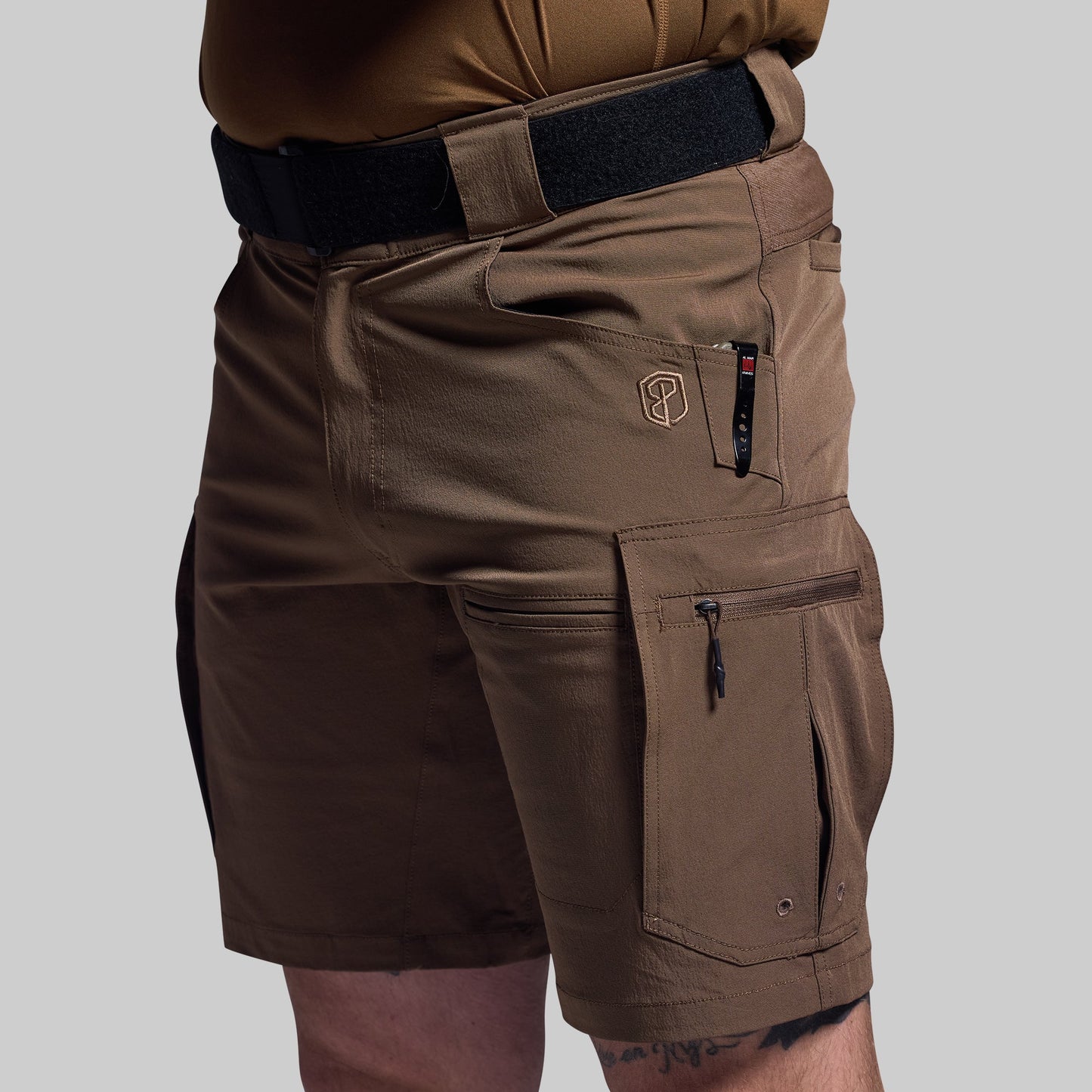 Brown tactical shorts with multiple pockets on a gray background