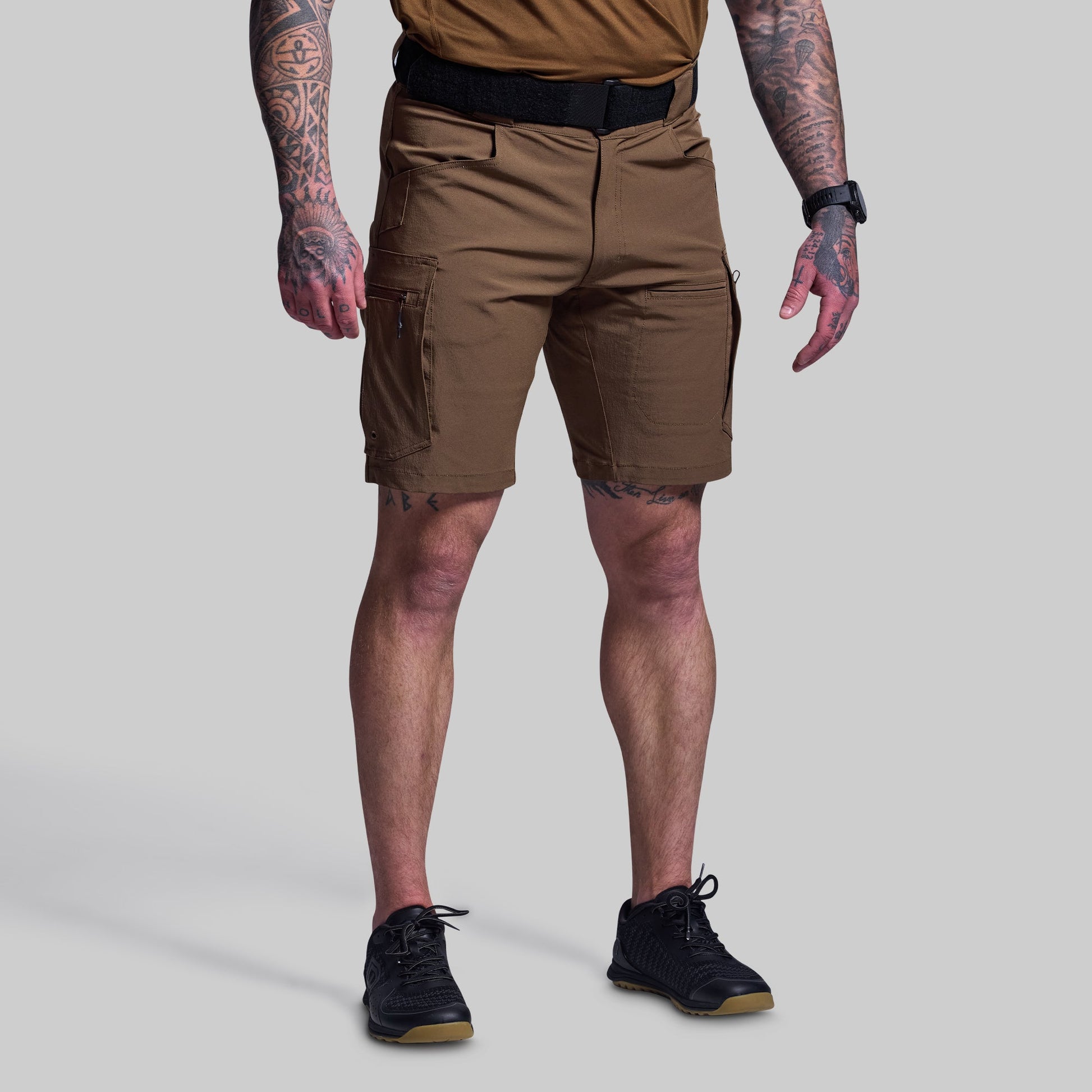Person wearing brown tactical shorts on a plain background