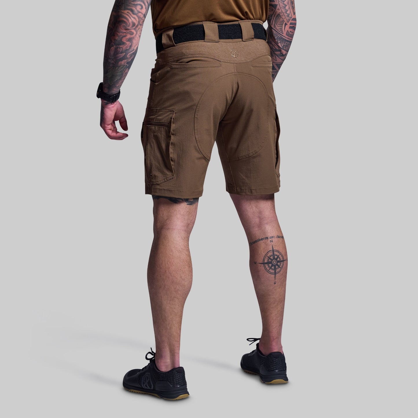 Person wearing brown tactical shorts on a light gray background