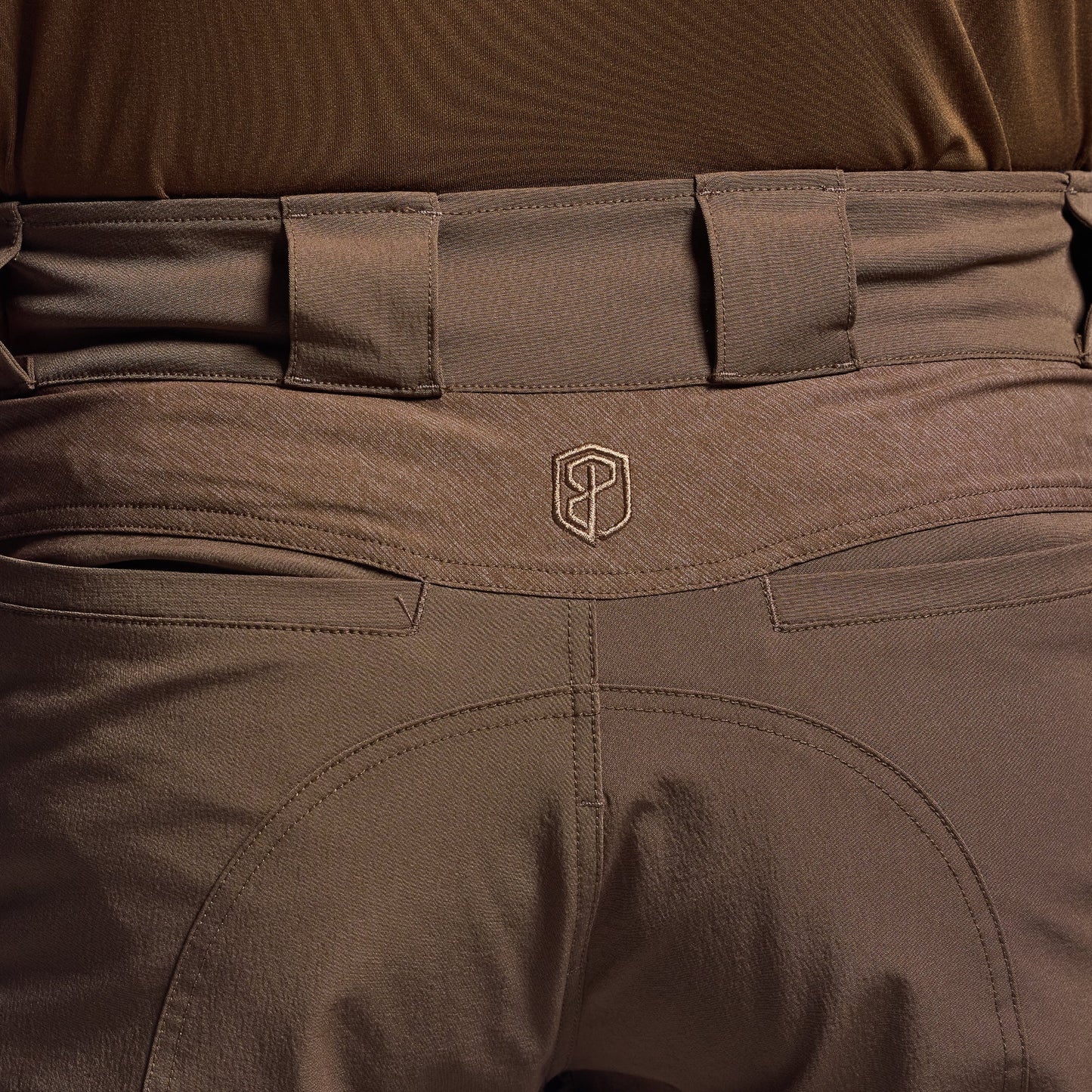 Close-up of brown tactical shorts with a visible brand logo on the waistband.