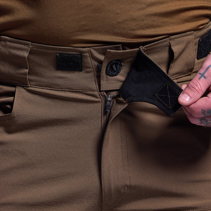 Close-up of brown tactical shorts with a hand adjusting the waistband.