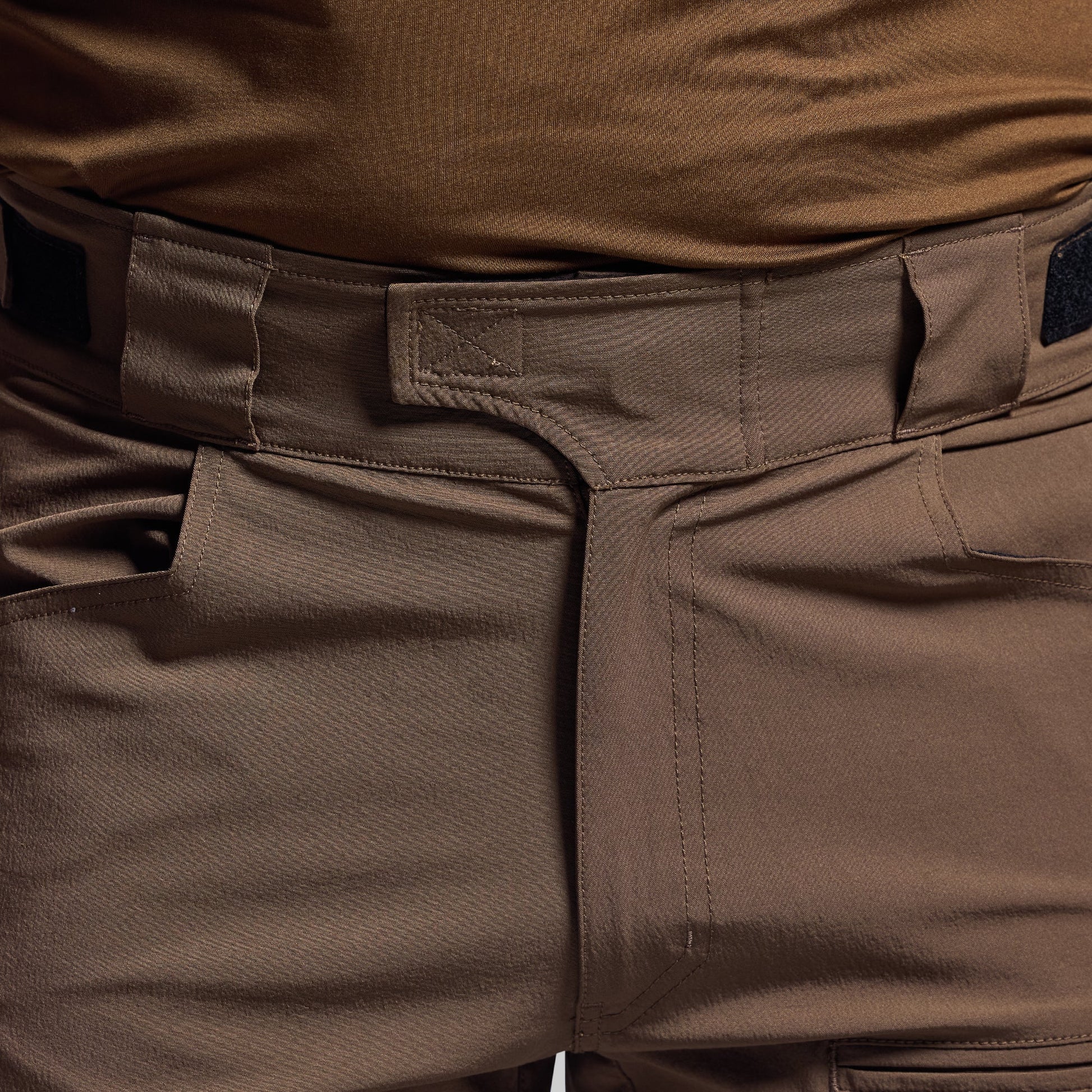 Close-up of brown tactical shorts with visible stitching and texture.