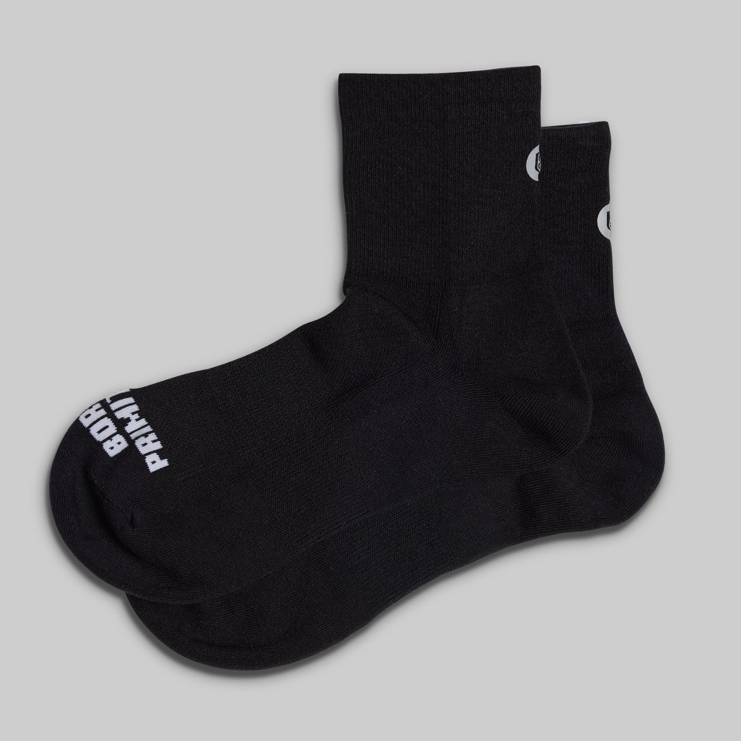 Black socks with white branding on a light gray background