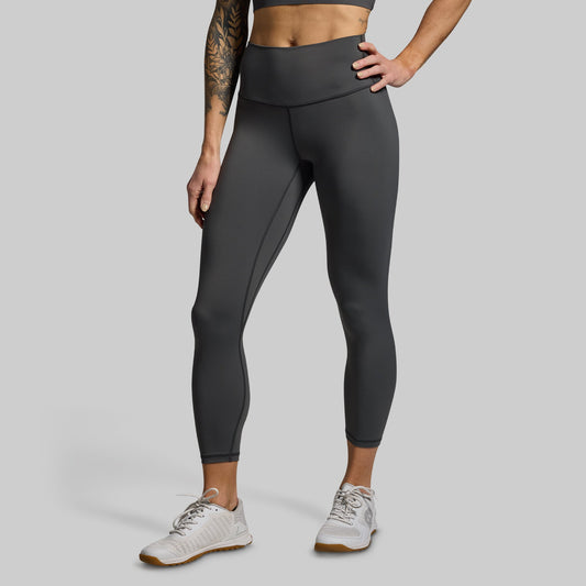Person wearing dark gray leggings on a light gray background