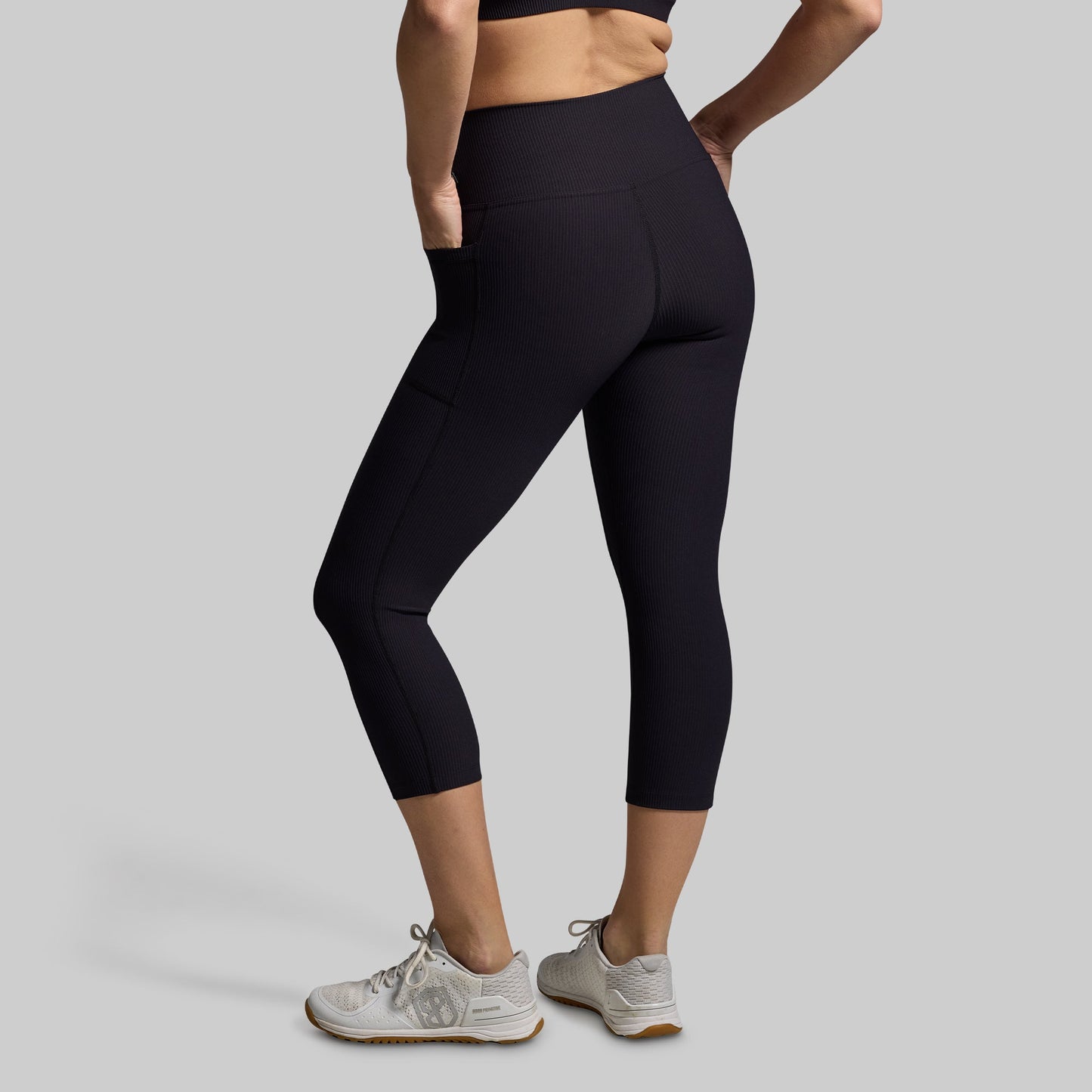 Woman wearing black capri leggings on a gray background