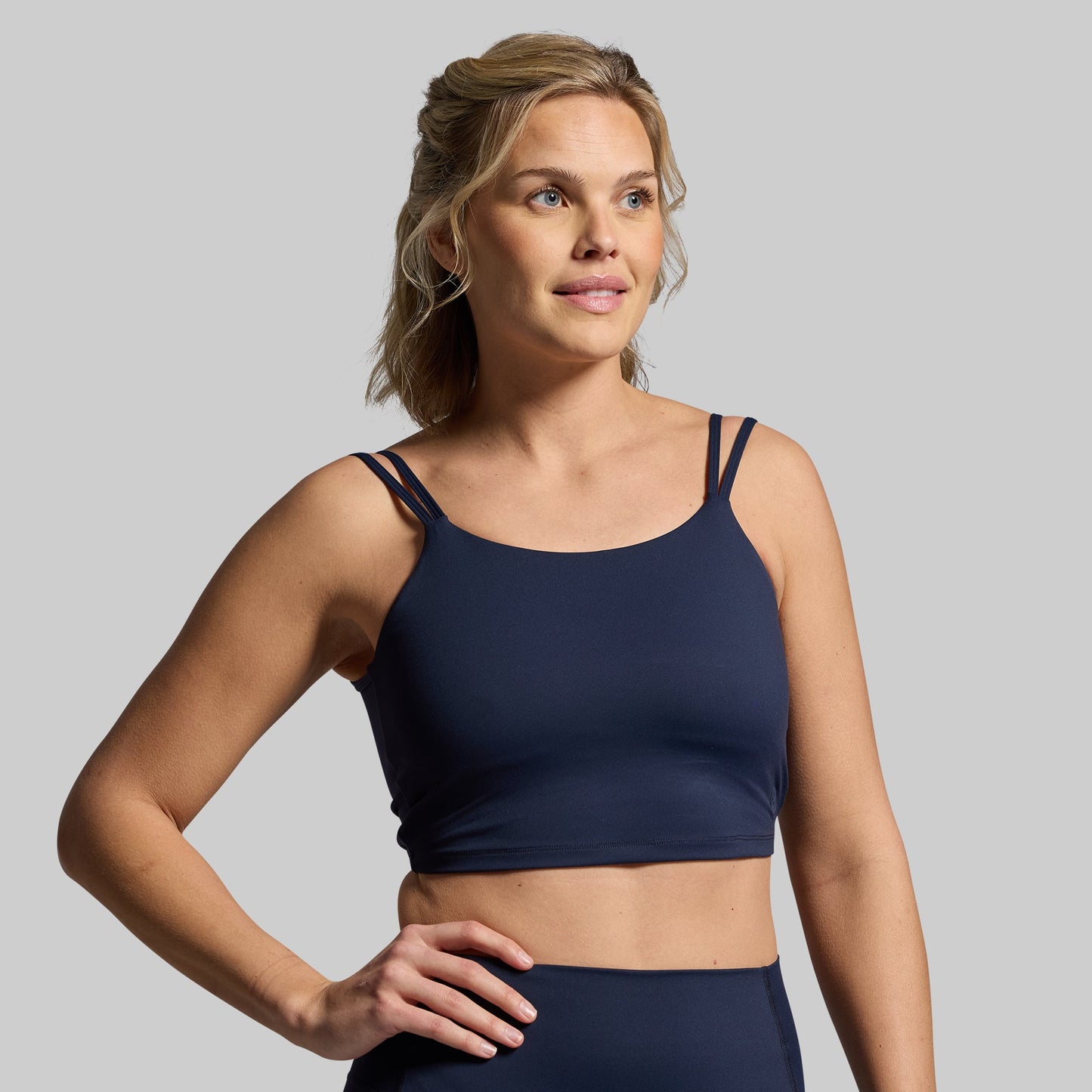 Woman wearing a navy blue sports bra on a gray background