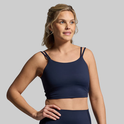 Woman wearing a navy blue sports bra on a gray background