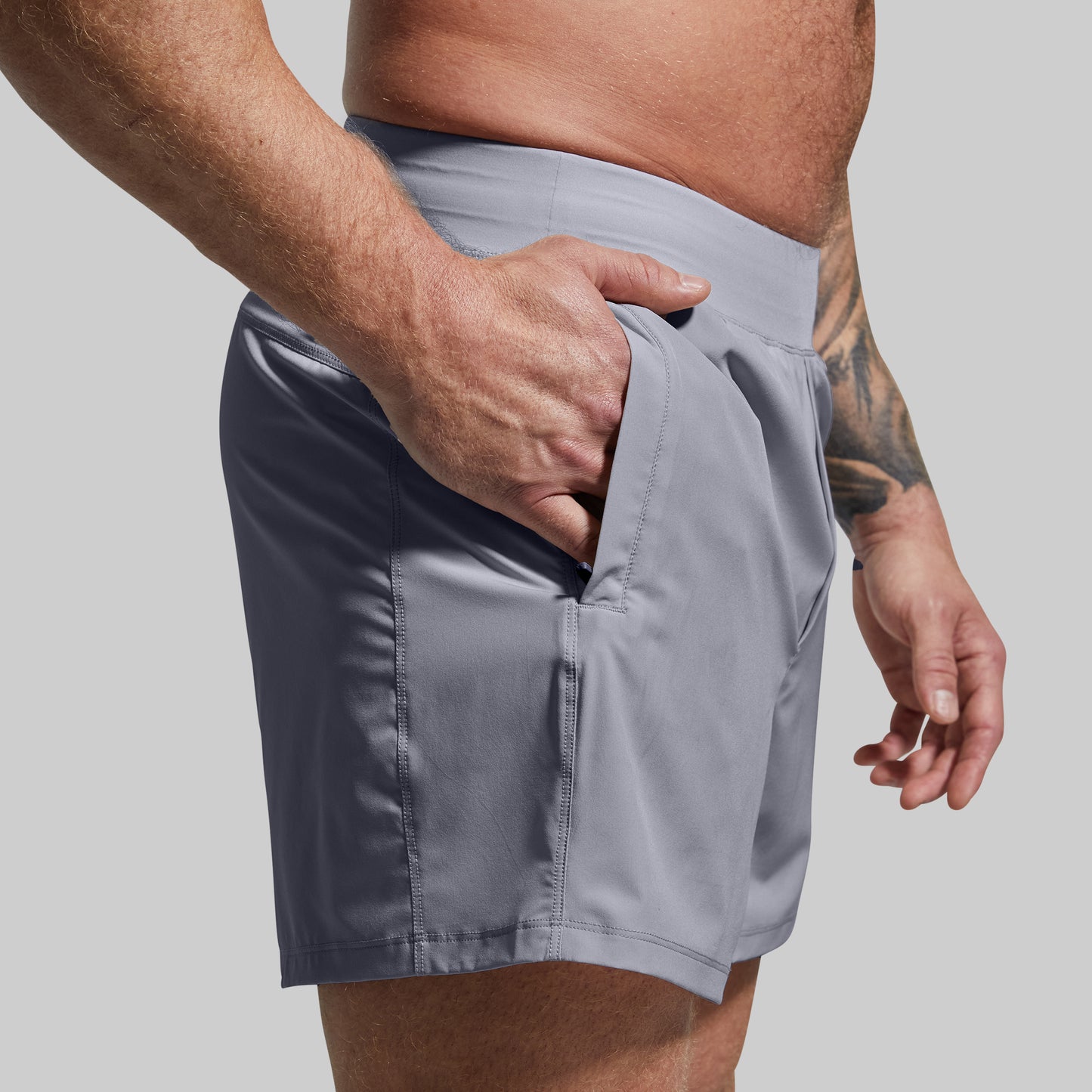 Person wearing gray shorts with a plain background
