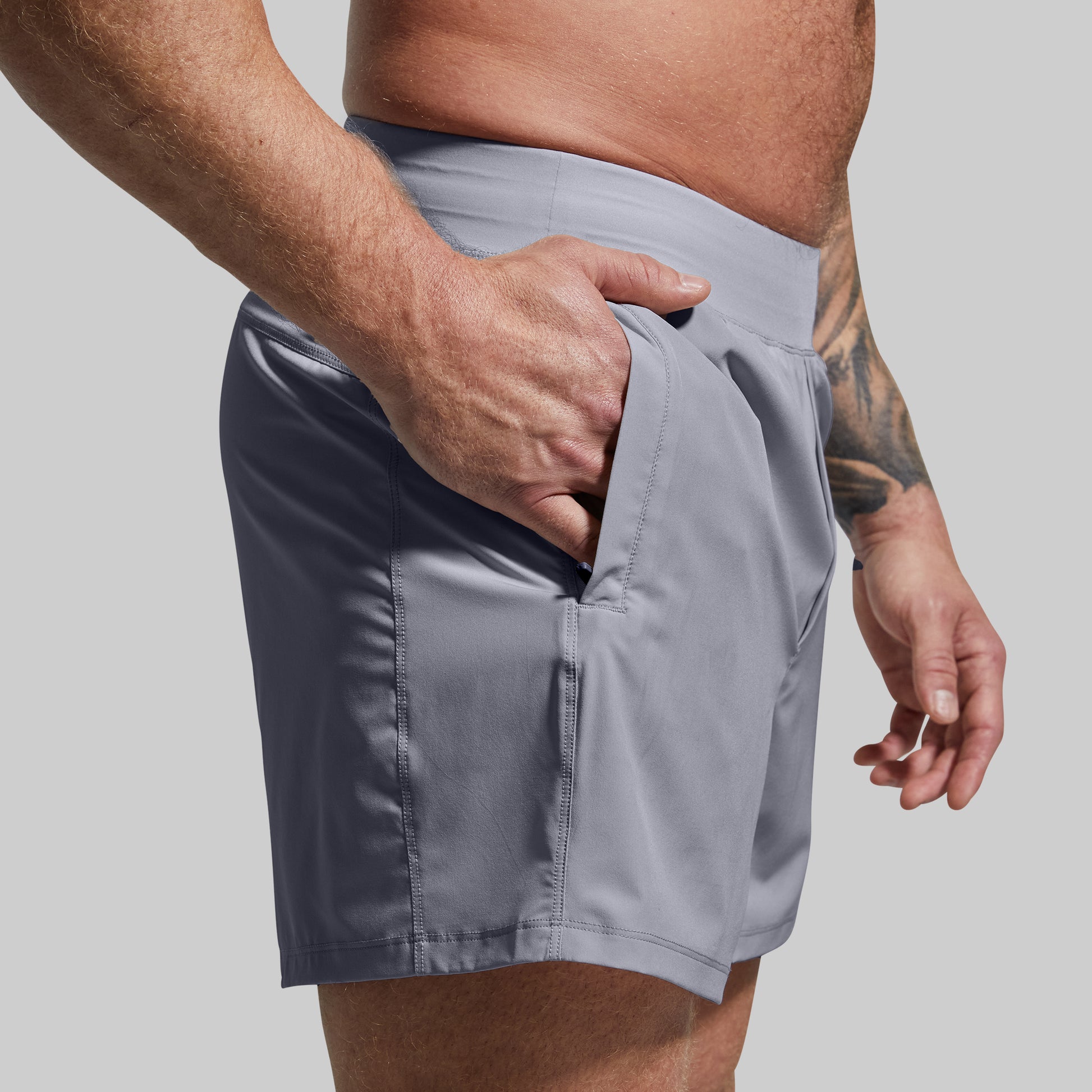 Person wearing gray shorts with a plain background
