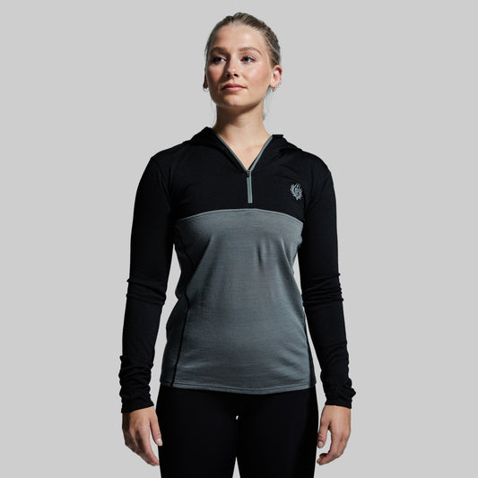 A woman wearing a black and gray Ridgeline Half Zip Hoodie with the brand logo on the chest.